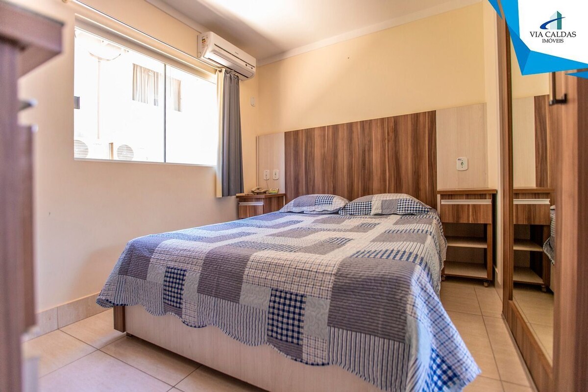 Un dormitorio con cama, mesitas de noche, armario y aire acondicionado.