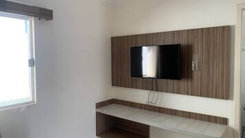 Casa de banho moderna com televisão montada, estantes embutidas e janela.