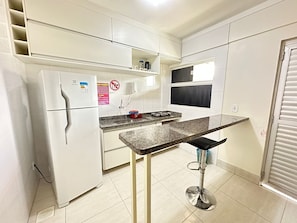 A compact kitchen with a built-in refrigerator, a gas stove, and a small countertop. - Lacqua DiRoma II Via Caldas (Caldas Novas)