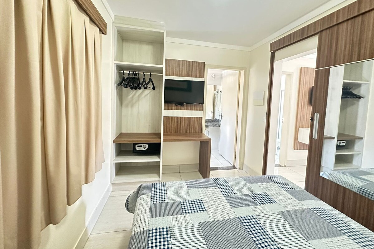 A bedroom with a bed, wardrobe, TV, and a bathroom door.
