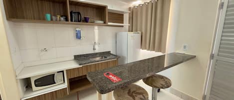 A modern kitchen with a built-in microwave, a sink, and a bar area with stools.