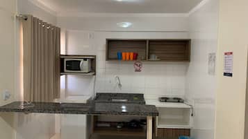 A compact kitchen with a built-in microwave, a sink, and a small refrigerator.
