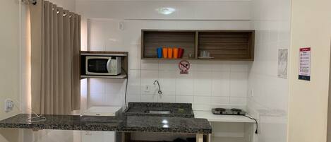 A compact kitchen with a built-in microwave, a sink, and a small refrigerator.