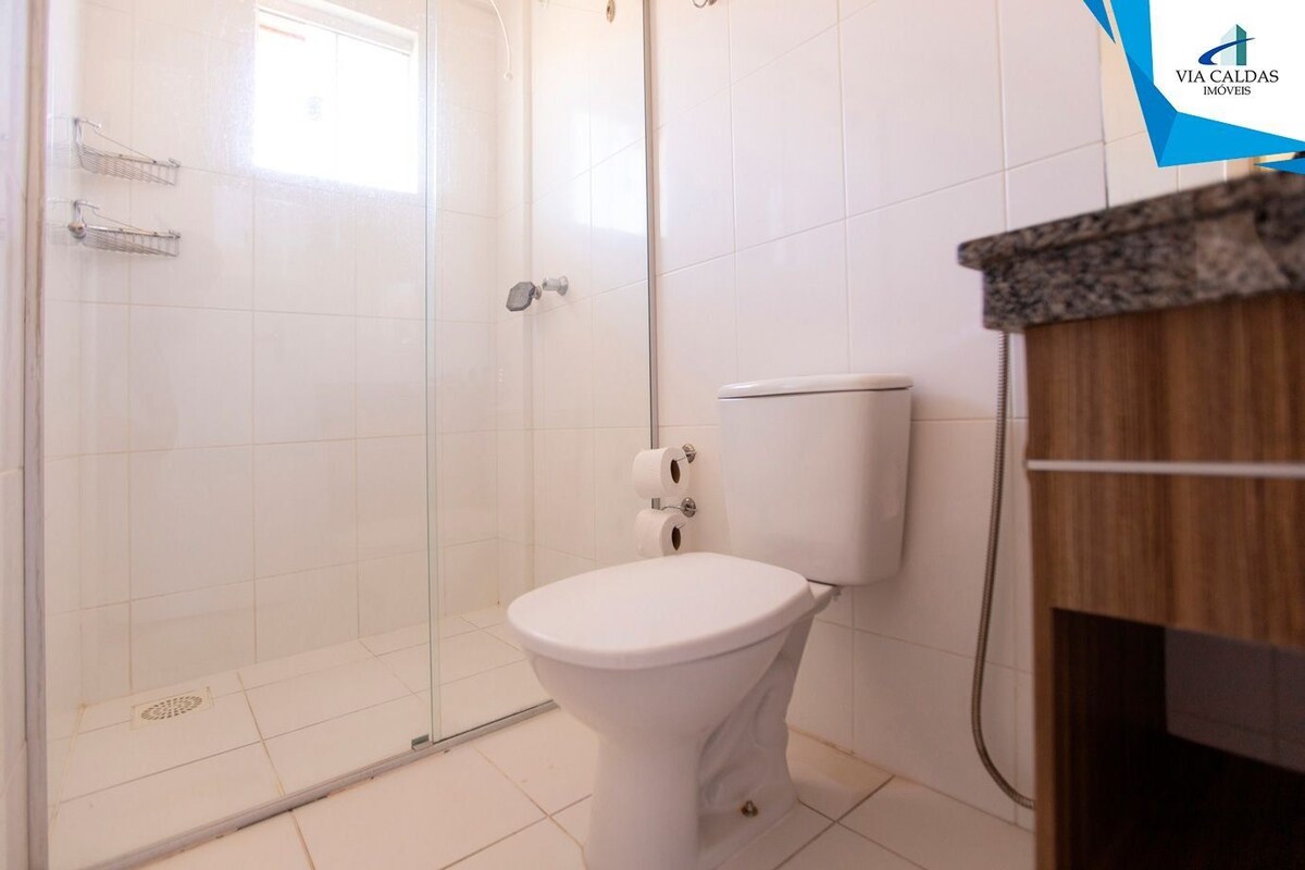 Un baño con cabina de ducha de vidrio, un inodoro blanco y un tocador de madera.