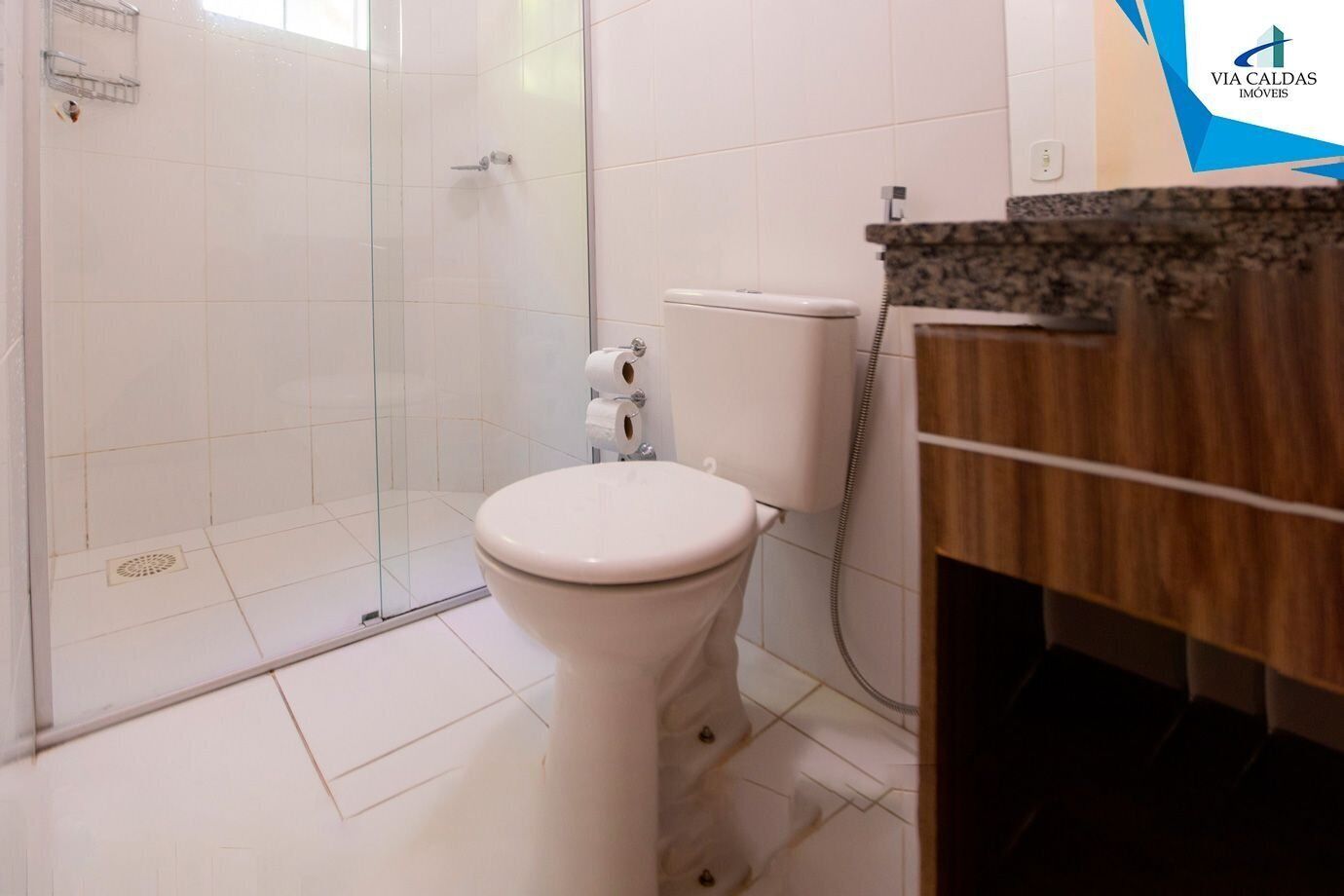 Un baño con inodoro, cabina de ducha y tocador con lavamanos.