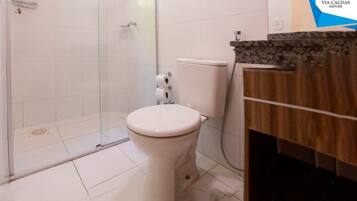 Un baño con inodoro, cabina de ducha y tocador con lavamanos.