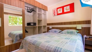 A bedroom with a bed, a wardrobe, a mirror, a bedside table, and a wall-mounted artwork.