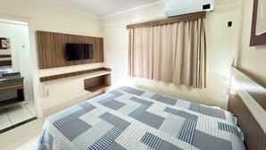 A hotel room with a bed, a TV mounted on a wooden panel, a window with curtains, and an air conditioning unit. - Lacqua DiRoma II Via Caldas (Caldas Novas)