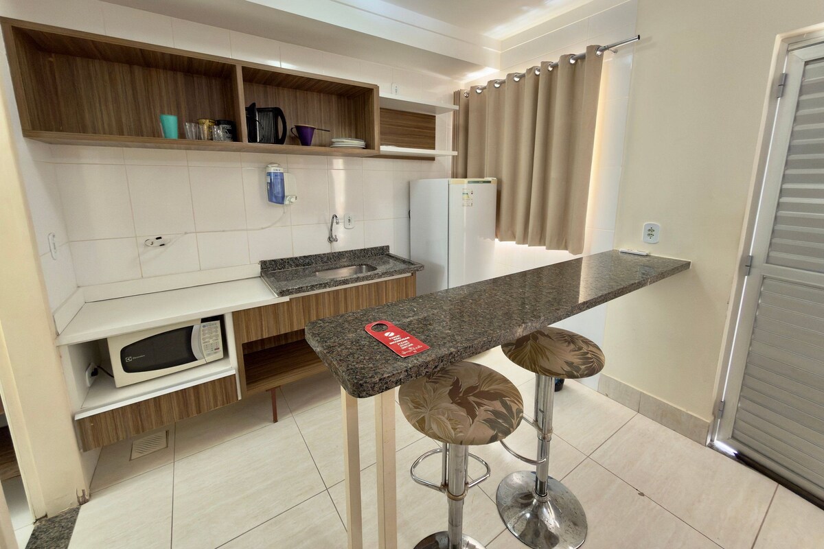 Una cocina moderna con microondas integrado, un lavabo y una barra con taburetes.