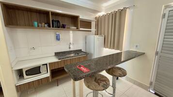 A modern kitchen with a built-in microwave, a sink, and a bar area with stools.