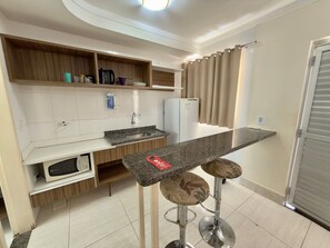 Una cocina moderna con microondas integrado, un lavabo y una barra con taburetes.