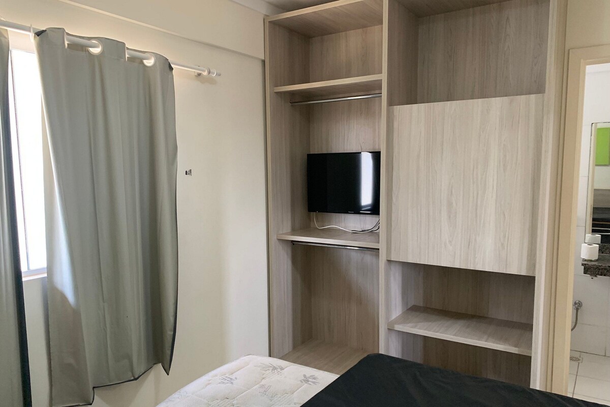 Un dormitorio con cama, televisor en un estante y armario.