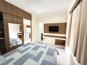 Una habitación de hotel con cama, televisor montado en la pared y armario.