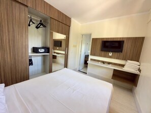 A hotel room with a bed, a wardrobe, a mirror, a TV, and a shelf with towels. - Lacqua DiRoma II Via Caldas (Caldas Novas)