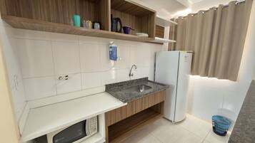 Cozinha equipada com micro-ondas, pia e frigorífico.