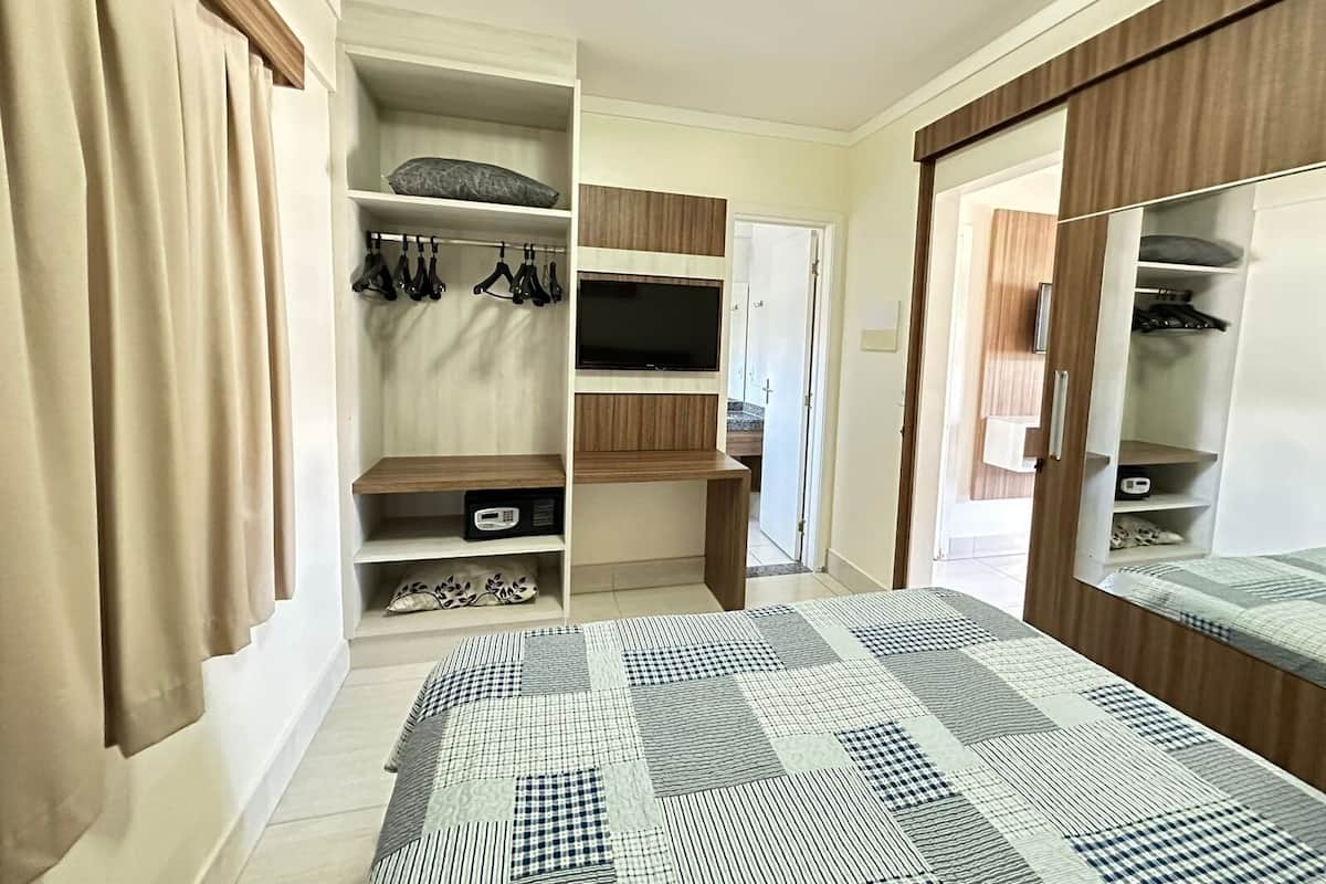 A bedroom with a bed, a wardrobe, a TV, and a bathroom.