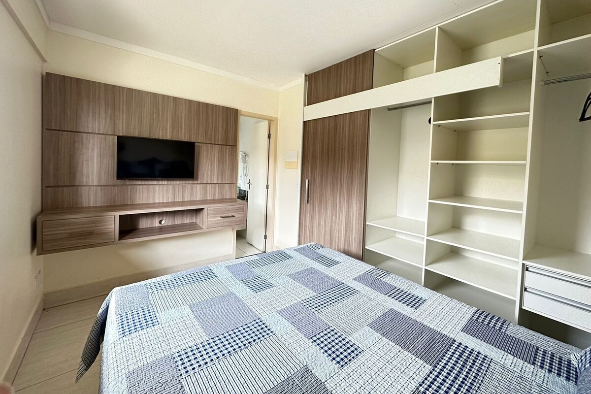 Un dormitorio con cama, televisión, armario y ropero.
