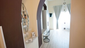 A hallway leading to a dining area with a chair and a shelf with items.