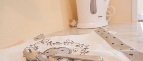 A kitchen counter with a white kettle, a spoon, and a cloth with a floral pattern.