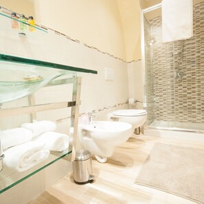 Une salle de bain moderne avec une étagère en verre où sont rangés les articles de toilette, un lavabo et des toilettes.