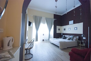 Une chambre à coucher comprenant un lit, des tables de chevet, une chaise et un luminaire suspendu.