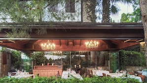 An outdoor dining area with multiple tables and chairs, a wooden pergola, and a large chandelier. - Ida Blue, Adatepe - Adults Only (Ayvacik)