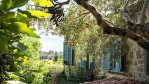 A stone building with green shutters, a tiled roof, and lush greenery. - Ida Blue, Adatepe - Adults Only (Ayvacik)