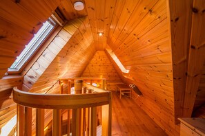 Een houten interieur met een schuine plafond, een wenteltrap en een kleine tafel.