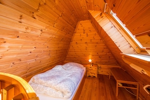 Een gezellig houten kamer met een bed, een klein bureau en een raam.