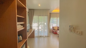 Une chambre d’hôtel équipée d’une armoire en bois, d’un téléviseur à écran plat, d’un canapé et d’une table à manger.