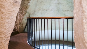 Un couloir voûté en pierre, doté d’un plancher en bois et d’une rambarde en métal.