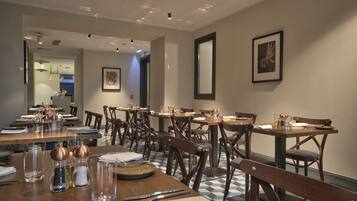 A dining area with multiple tables and chairs, arranged in a spacious layout.