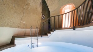 Un escalier en colimaçon avec une rampe métallique, menant à une porte en arc de cercle.