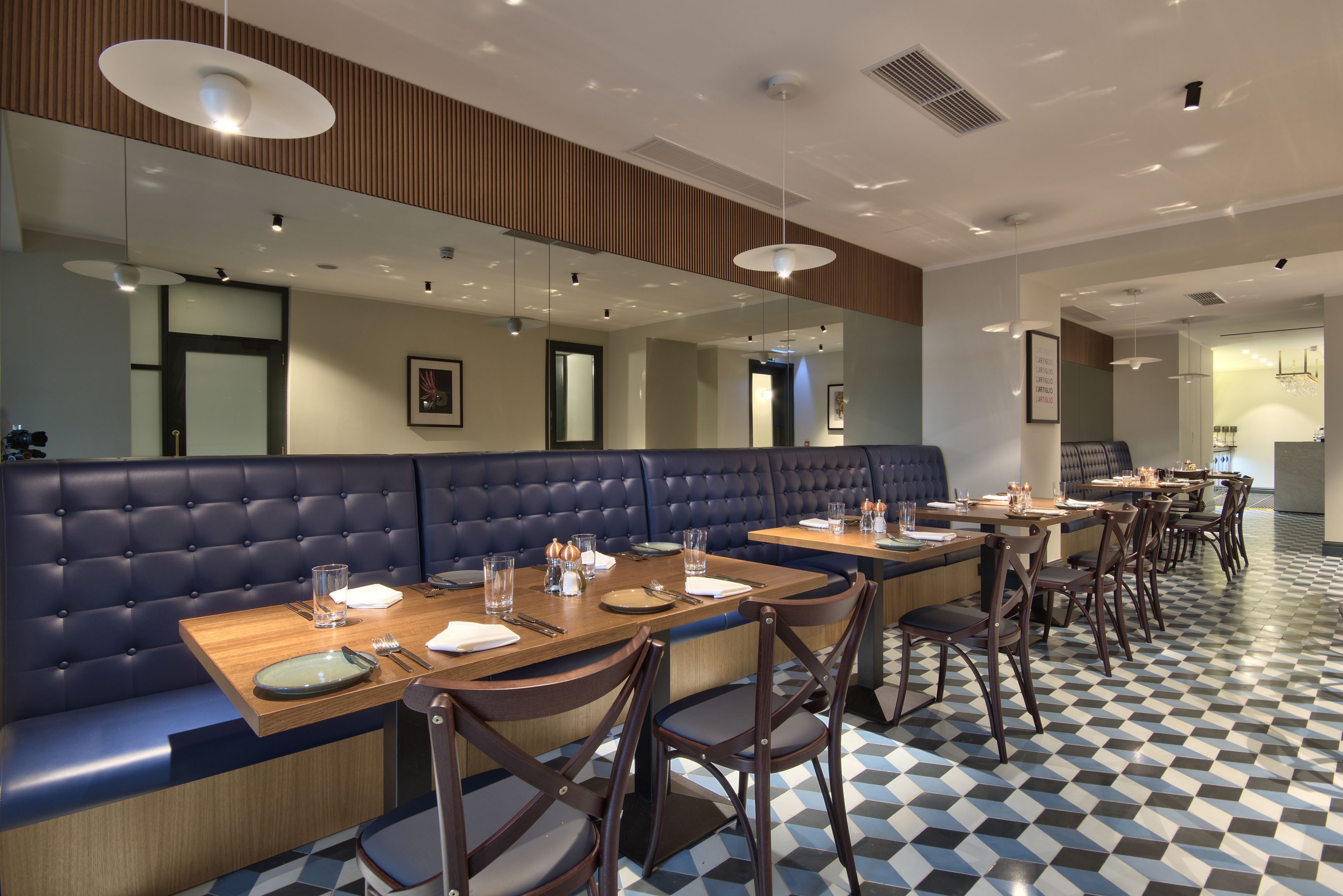 A restaurant with a checkered floor, wooden tables, and blue upholstered booths.
