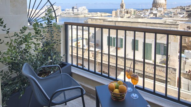 Un balcon avec une table, des chaises et un panier de fruits.