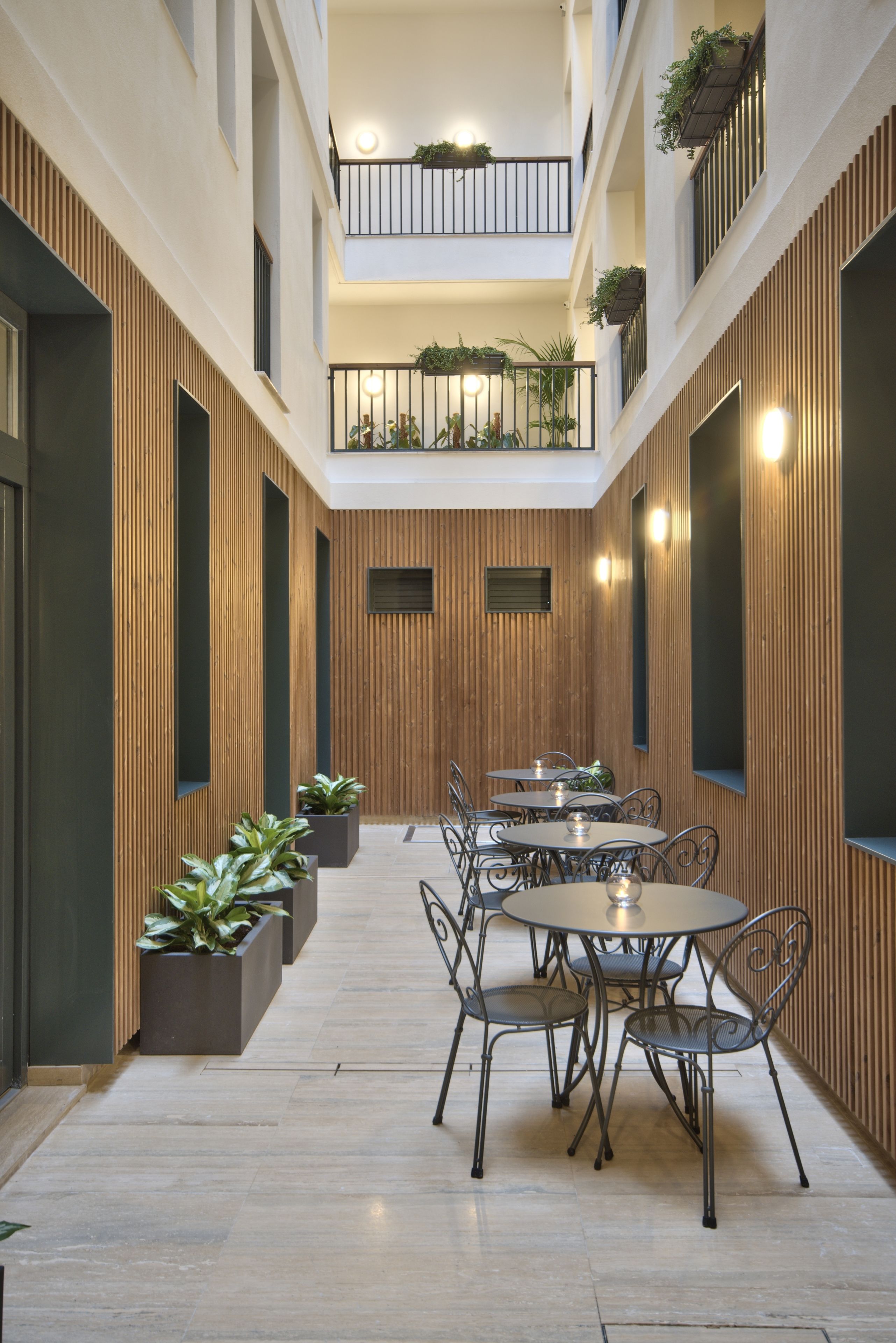 Un espace intérieur moderne doté d’un coin repas central, de lambris en bois et de plantes en pot.