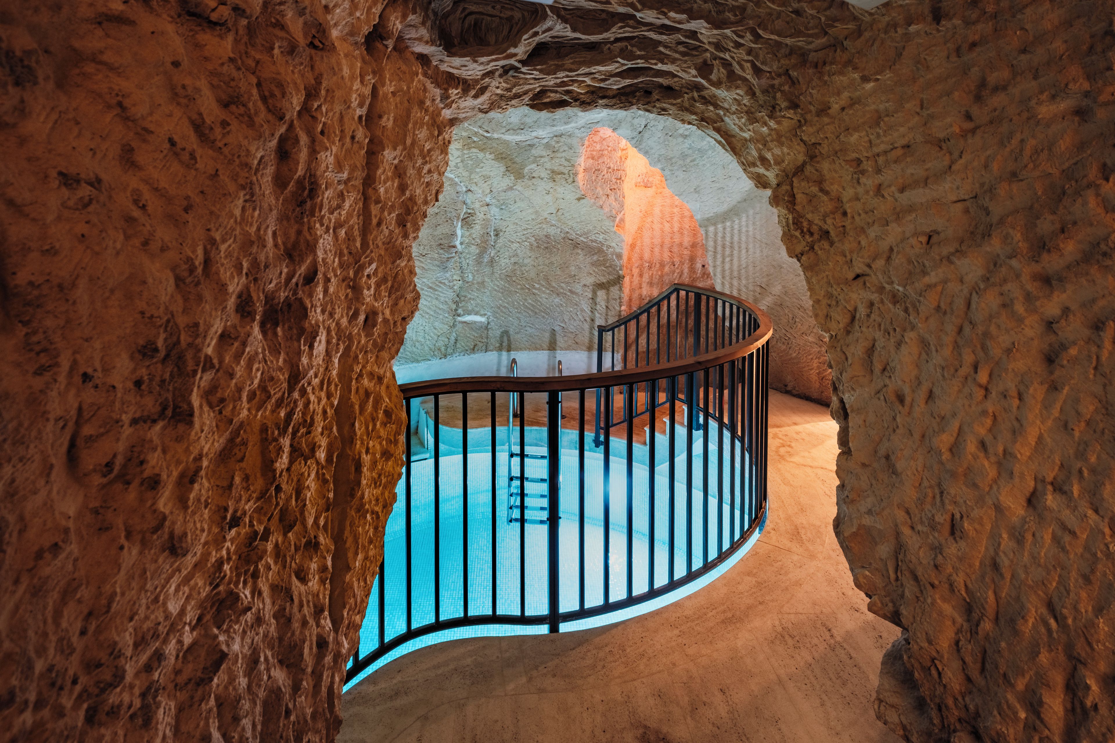 A pool area with a curved railing, surrounded by rocky walls.