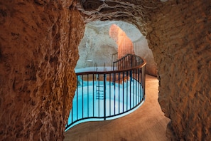 Zona de piscina con barandilla curva, rodeada de paredes rocosas.