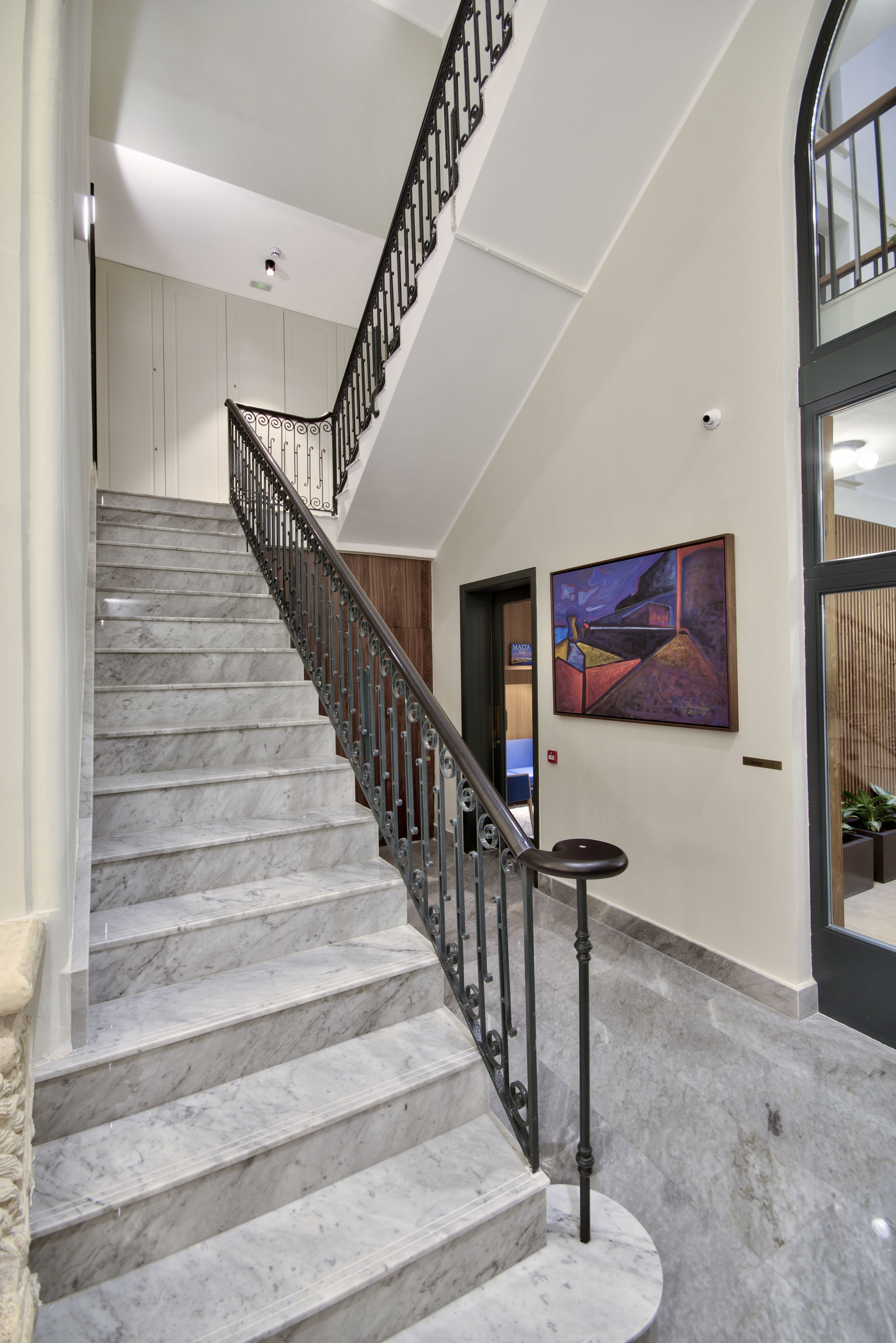 Una escalera de mármol con barandilla de metal negro que conduce a una plataforma.