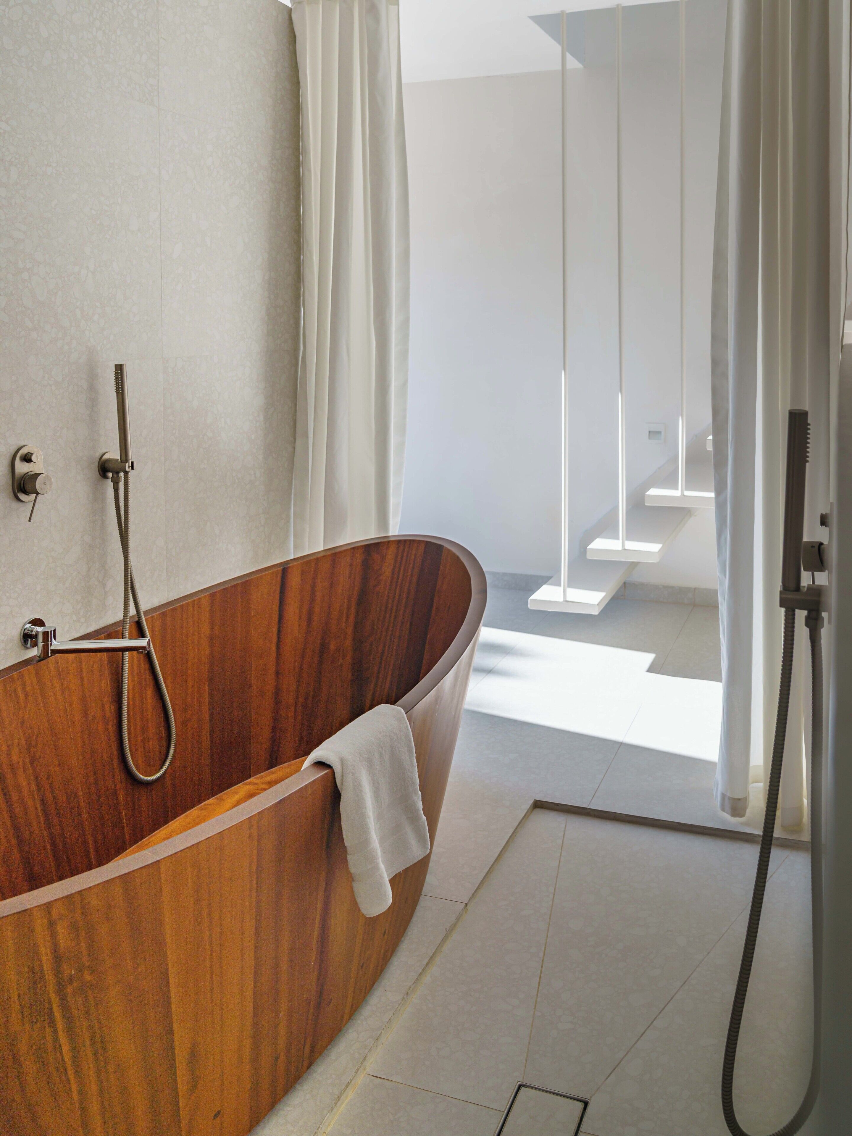 Une salle de bain moderne avec une baignoire en bois, une douchette à main et une cabine de douche en verre.