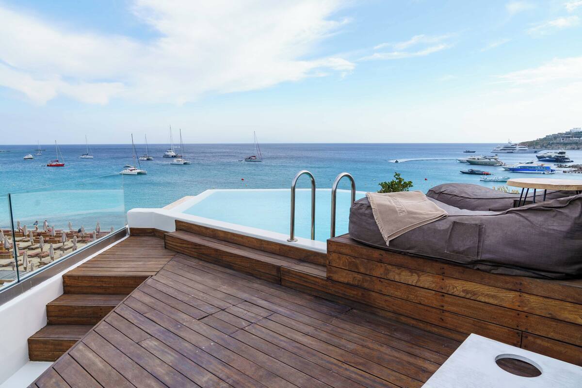 Una terraza de madera con piscina, con vistas a un puerto deportivo con barcos.