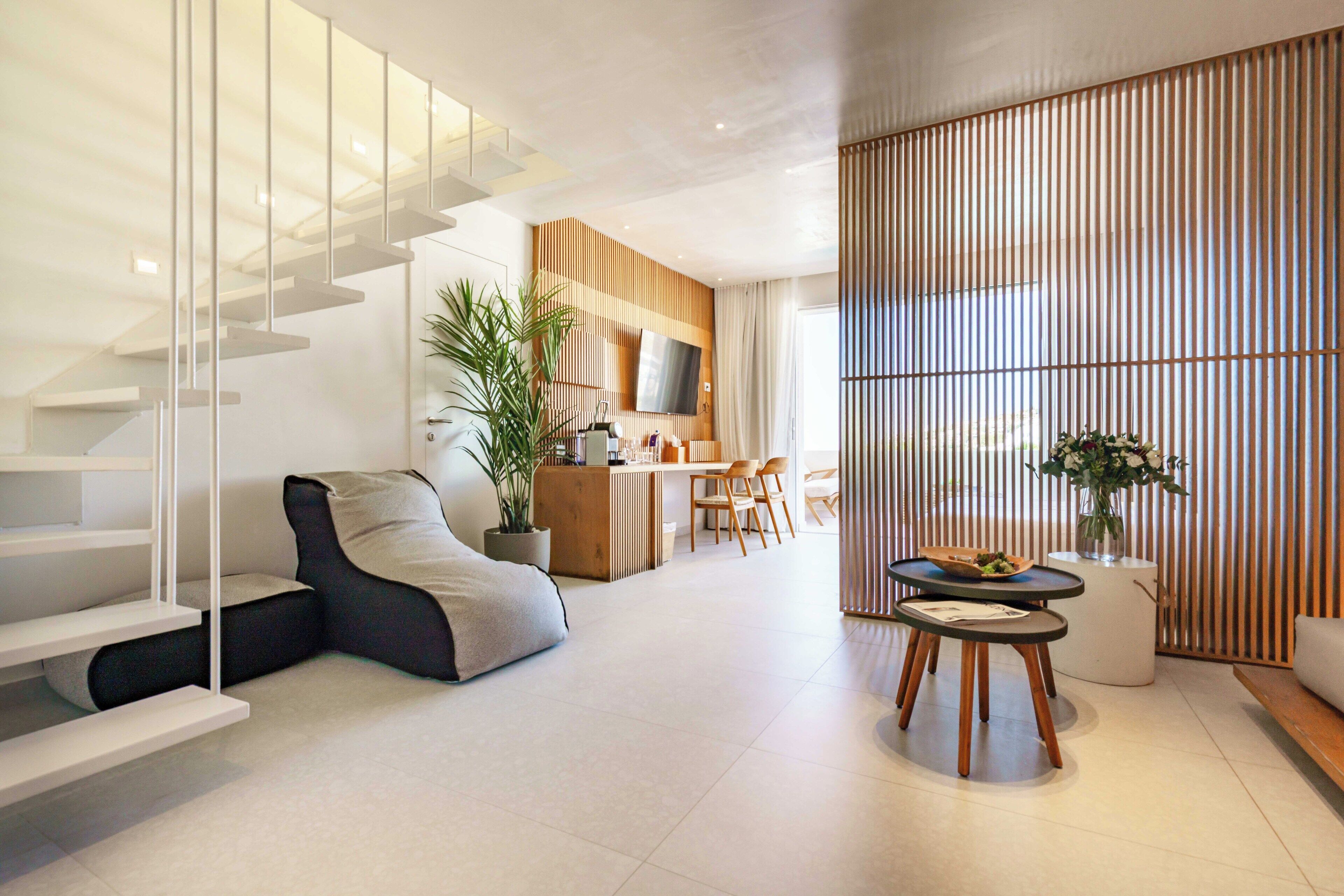 A modern living room with a staircase, a dining area, and a kitchen in the background.