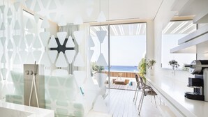 A modern bathroom with a large bathtub, a shower, and a glass-enclosed seating area with a view of the ocean. - Mykonos Dove Beachfront Hotel (Mykonos)