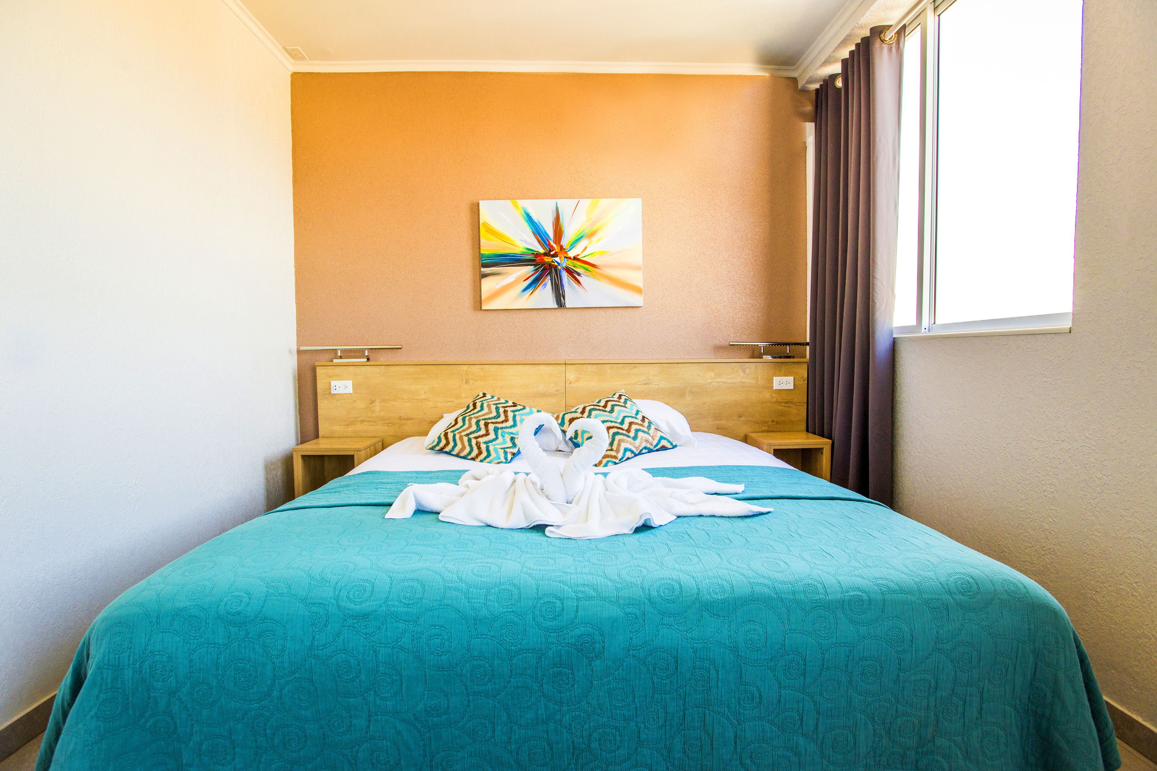 Ein Hotelzimmer mit Bett, einem Wandbild und einem Vorhangfenster.