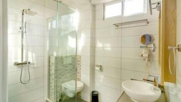 Un baño moderno con cabina de ducha de vidrio, inodoro y bidé.