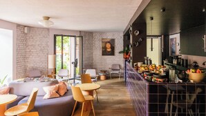 Una sala de estar moderna con una pared de piedra, un ventanal grande y una zona de cocina con barra.