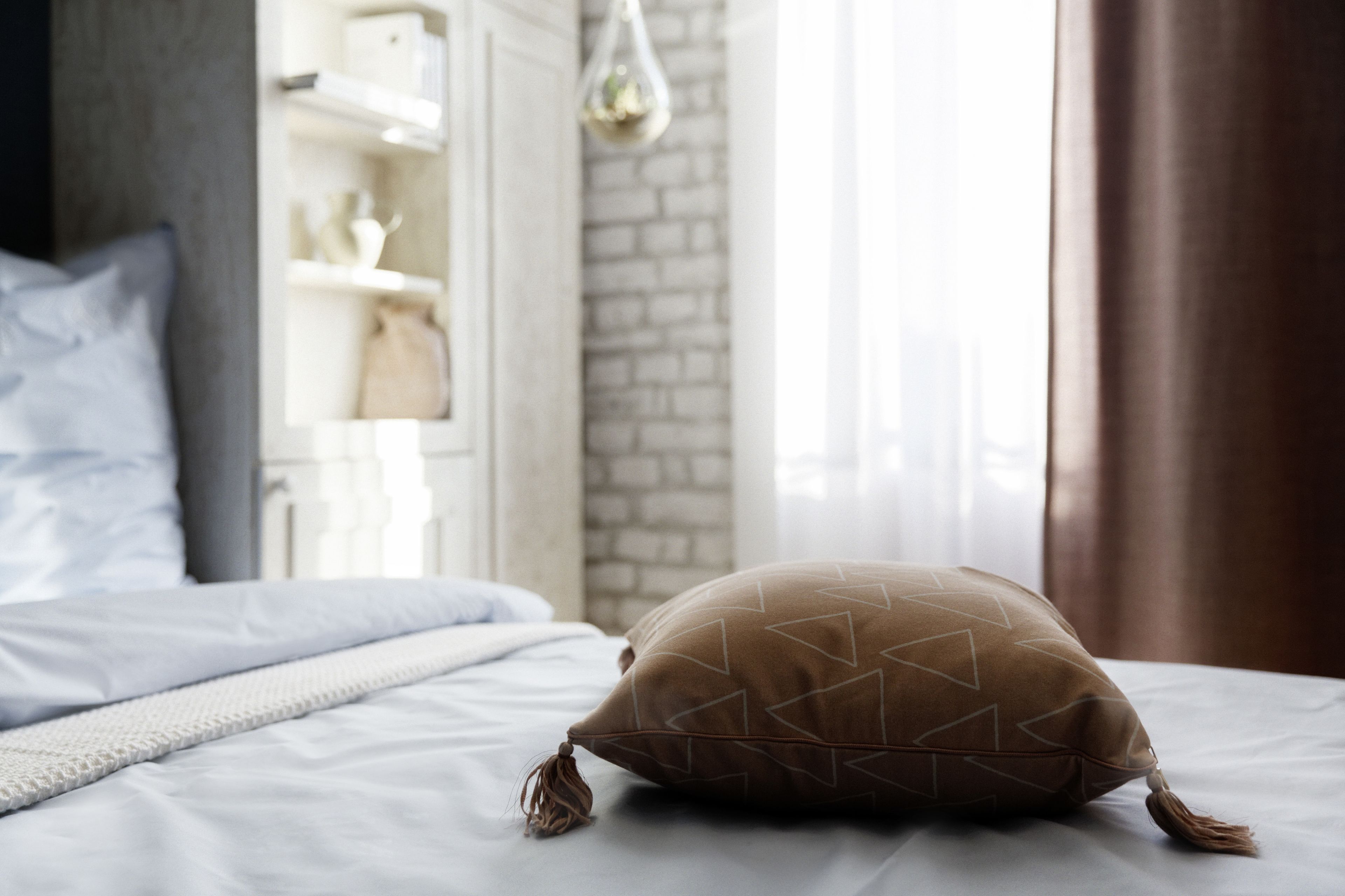 A neatly made bed with a patterned pillow and a white blanket.