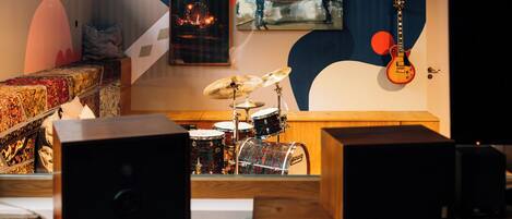 A music studio with a drum set, a guitar, and a mixing console.