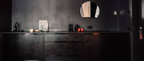 A modern kitchen with a dark wood cabinet, a round mirror, and a framed picture on the wall.