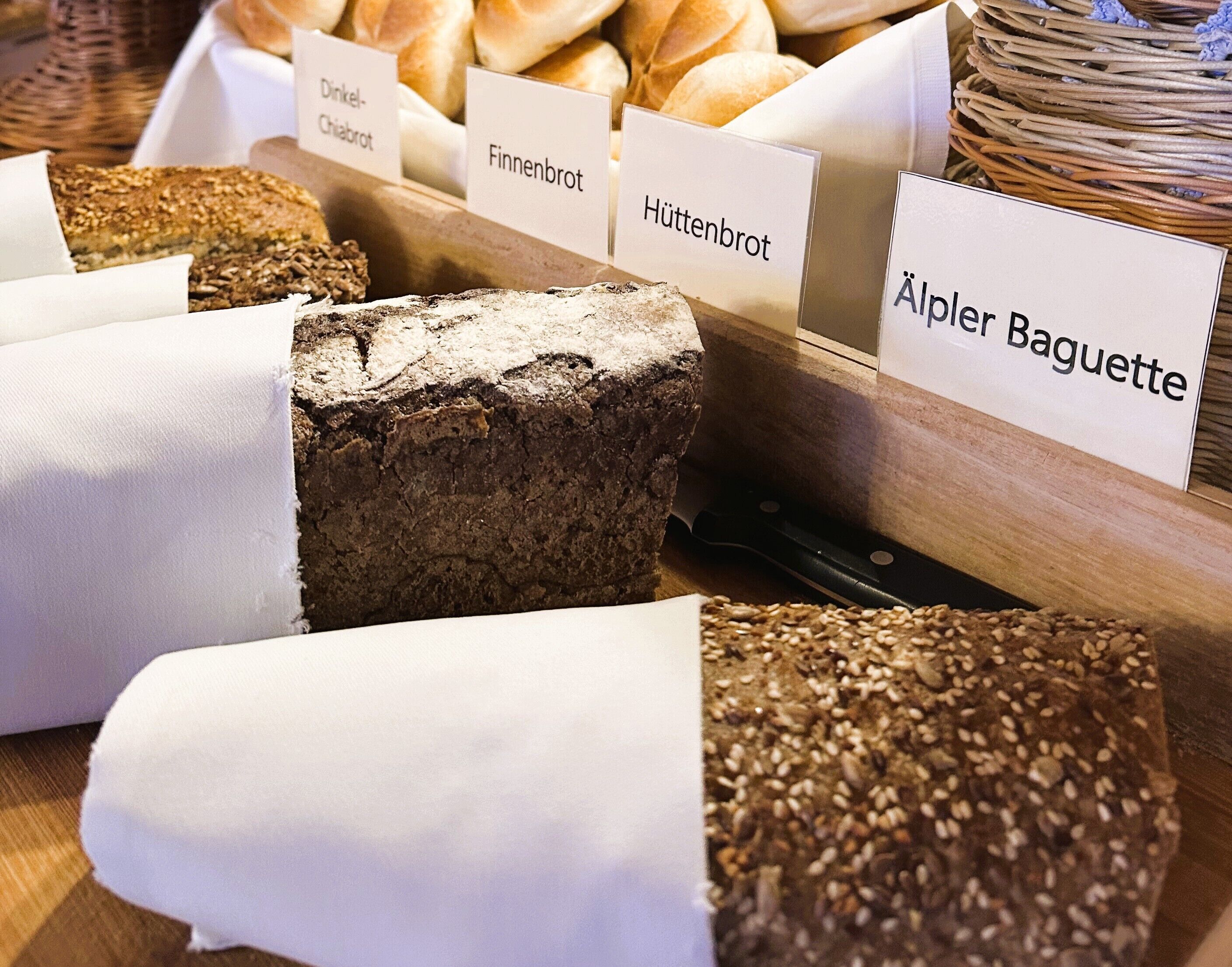 A variety of bread types labeled in a bakery setting.
